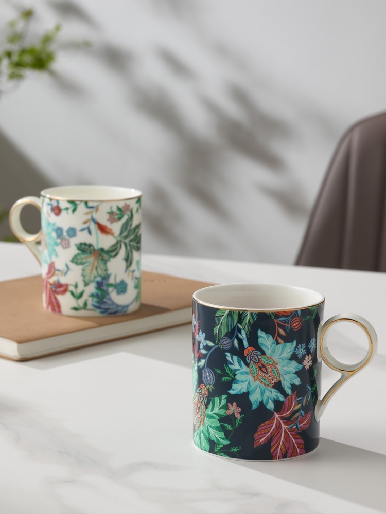 Clarence Mug Set of Two (350ml), panoramic display of two‑tone dark‑jungle floral gold‑trim bone‑china mugs on soft‑light white tabletop with wooden tray